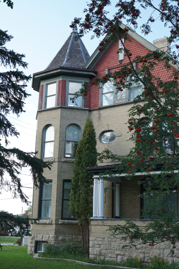 The corner tower of Myers House with trees in the foreground obscuring part of the facade.