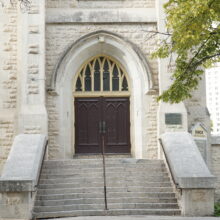 Image 4: Multiple steps leading up to the gothic style arched wooden front doors