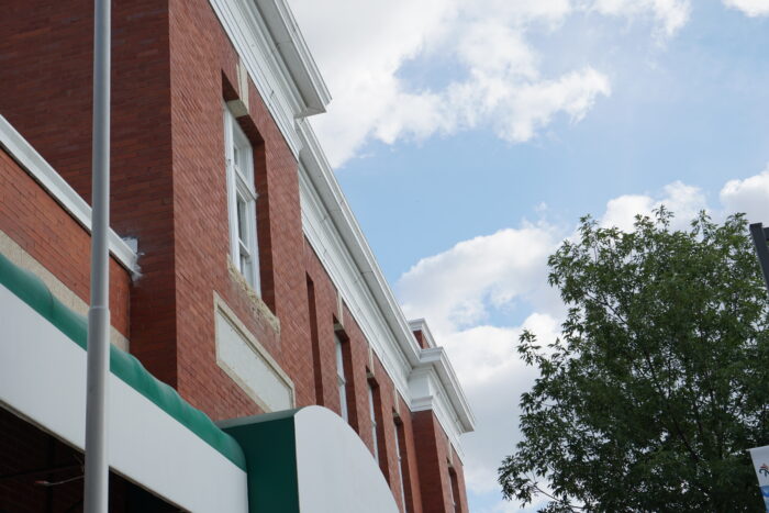 Looking up at the roofline of the Neepawa Post Office. A tree is beside the building.