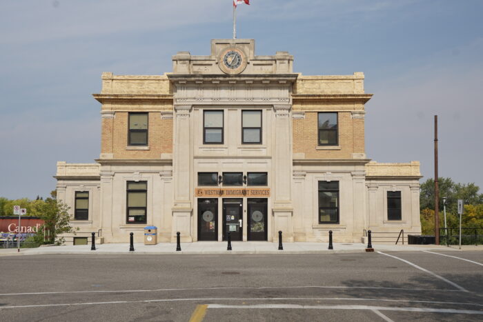 Brandon’s Canadian Pacific Railway Station building. The sign above the doors reads “WESTMAN IMMIGRANT SERVICES.”