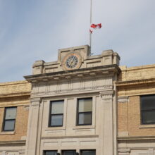 Image 3: Looking up at two windows and clock above the front entrance of Brandon’s CPR Station