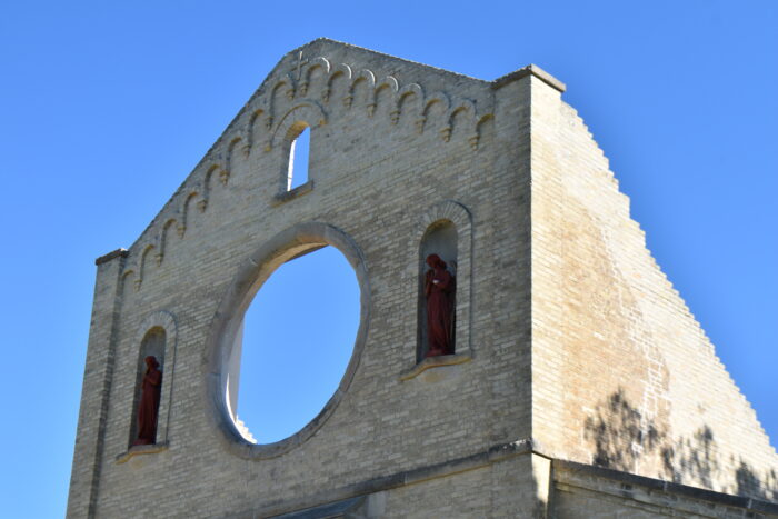 The opening for the rose window, framed by two angel statues, above the entrance of the Trappist Monastery Church.