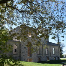 Image 15: Front yard of the Trappist Monastery Church with trees obscuring view.