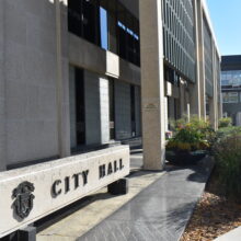 Image 4: Sign in front of the building that reads "City Hall" with the facade of the building in view