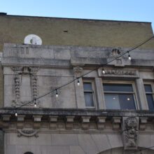 Image 2: Looking up at the facade of the Walker Theatre building featuring ornamental details of the cornice and around the windows