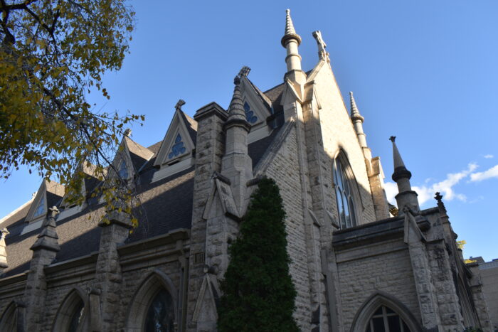 Holy Trinity Church with a cedar tree growing up along the facade.