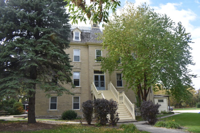 A sidewalk and stairs lead up to the Sisters of the Holy Name Convent with trees in front of the building.