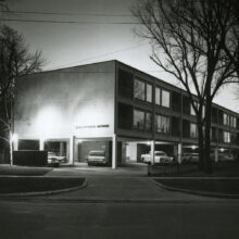 Image 3: Night view of Executive House apartments with cars in lower-level lot