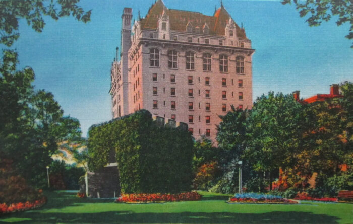 A postcard of the Fort Garry Hotel with the old Upper Fort Garry gate and trees in front.