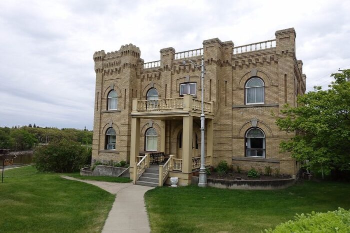 The Hillcrest Museum with a light on a pole next to the front entrance. A river flows beside the building.