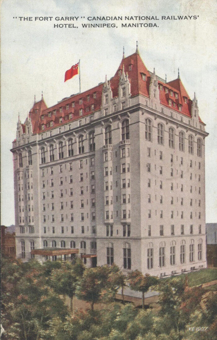 A postcard depicting the Fort Garry Hotel with a flag flying on the roof and trees in front.