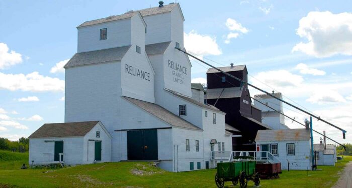 Three grain elevators in Inglis. The elevator in the foreground reads “RELIANCE” and “RELIANCE GRAIN CO. LIMITED.”