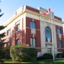 A Canadian flag flies on a flagpole in front of the Carman Memorial Hall.