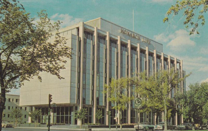 The Monarch Life Building with “MONARCH LIFE” along the top of the facade. Vintage vehicles are in front.