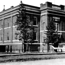 Image 2: The Court House in The Pas with several coniferous trees growing in front