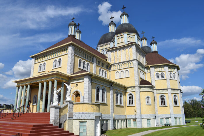 Front of Ukrainian Catholic Church of the Immaculate Conception. A light-yellow building with iron crosses topping multiple onion-shaped domes.