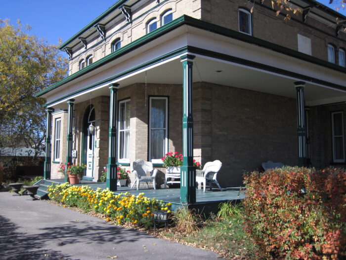 The front verandah of Fleming House. Deck furniture and potted flowers sit on the verandah.