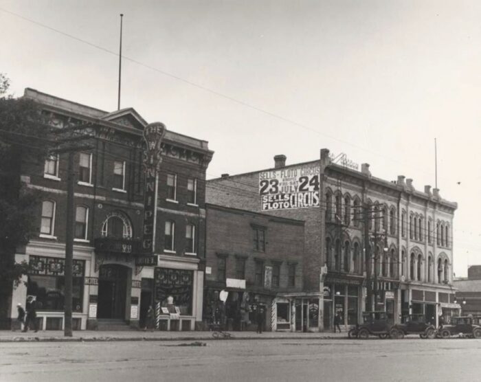 The Winnipeg Hotel in 1926 with two buildings beside it. A sign reading “WINNIPEG HOTEL” projects from the front façade.