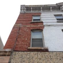 Close-up of the Winnipeg Hotel facade showing the white-painted bricks next to the original brick color.